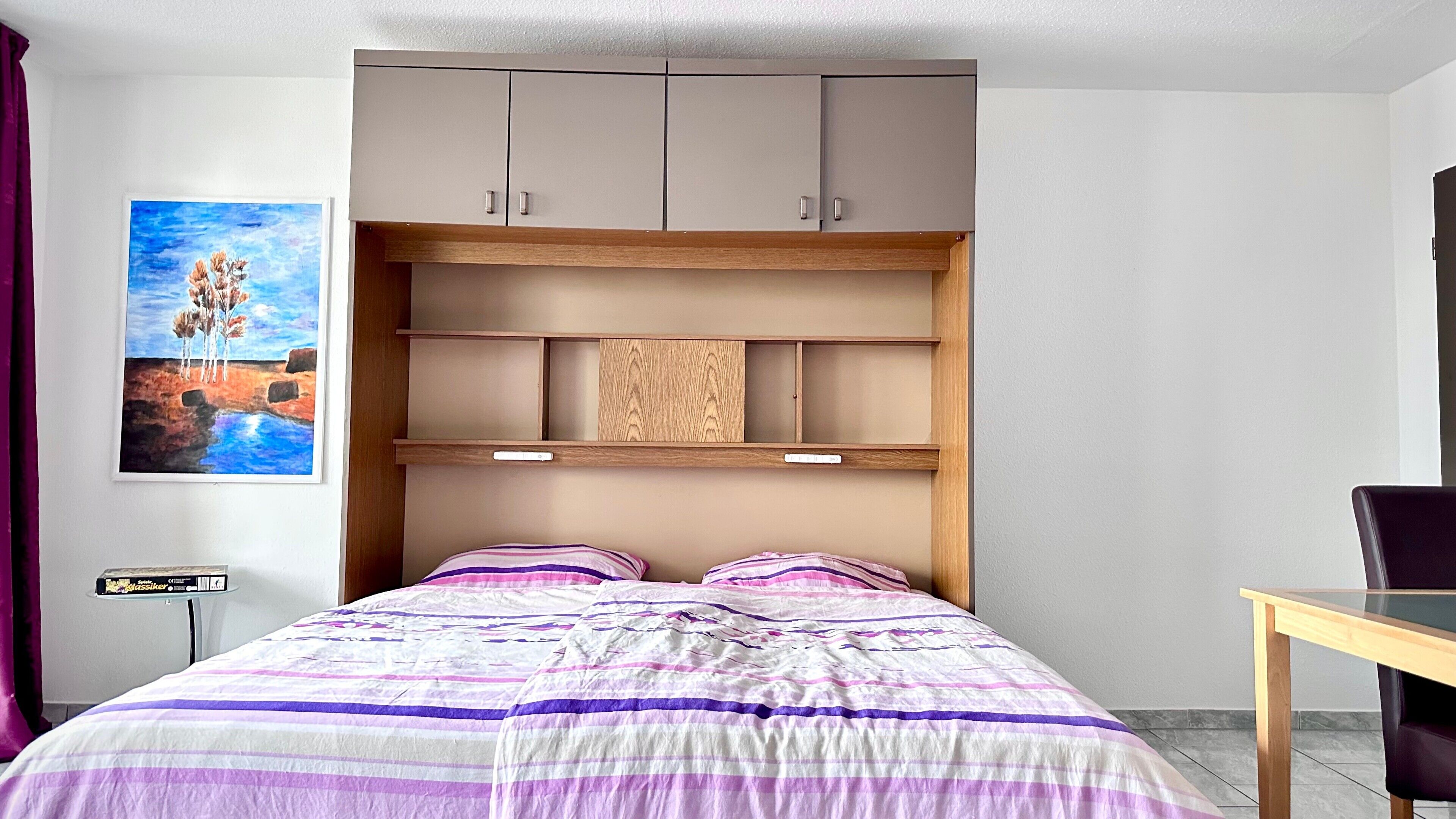 Un dormitorio con cama, escritorio y aparador.