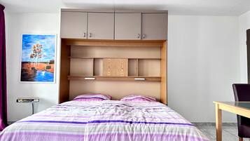 Un dormitorio con cama, escritorio y aparador.