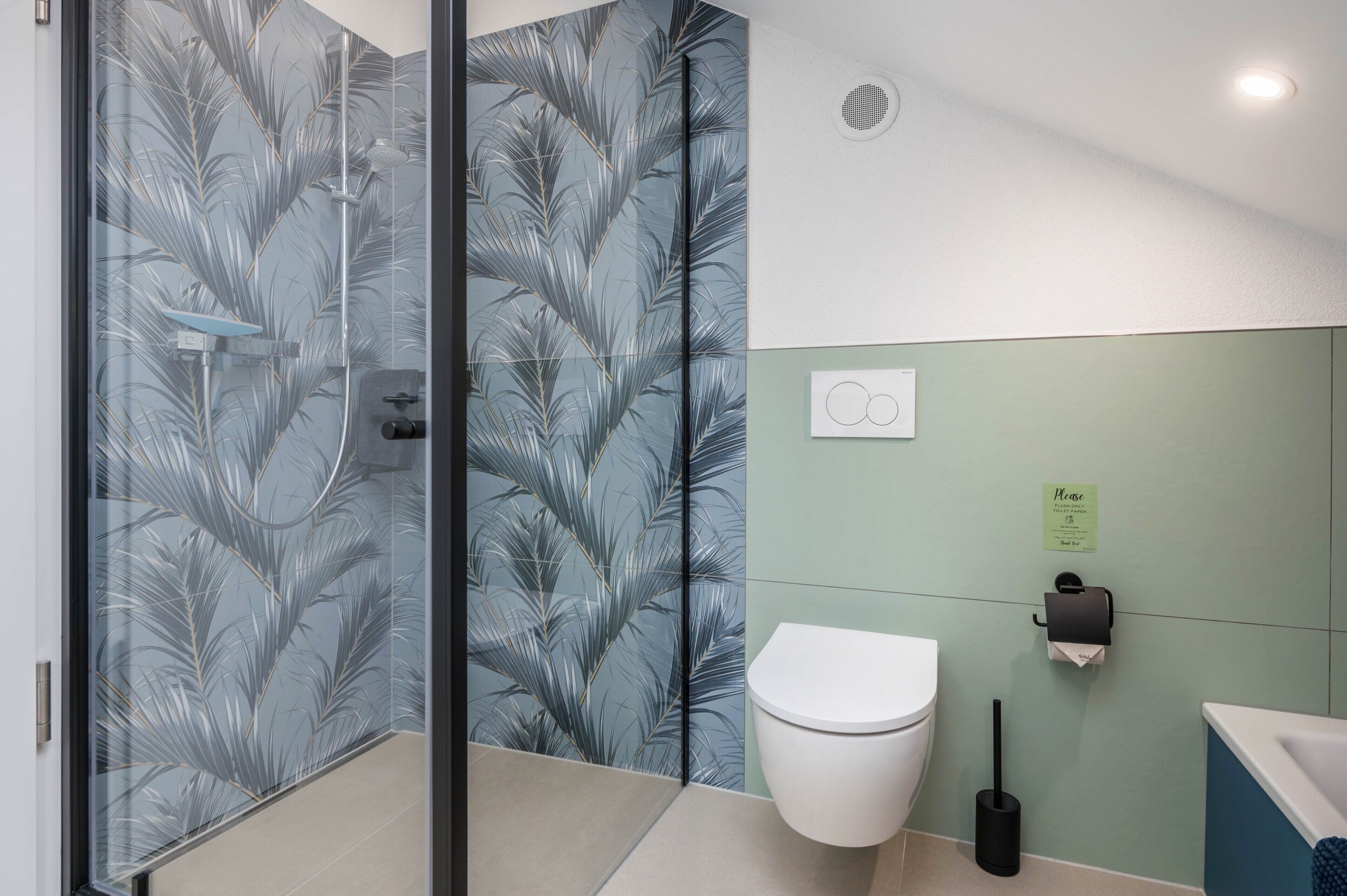 Une salle de bain moderne dotée d’une douche à parois de verre, de toilettes, d’un bidet et d’un sèche-mains.