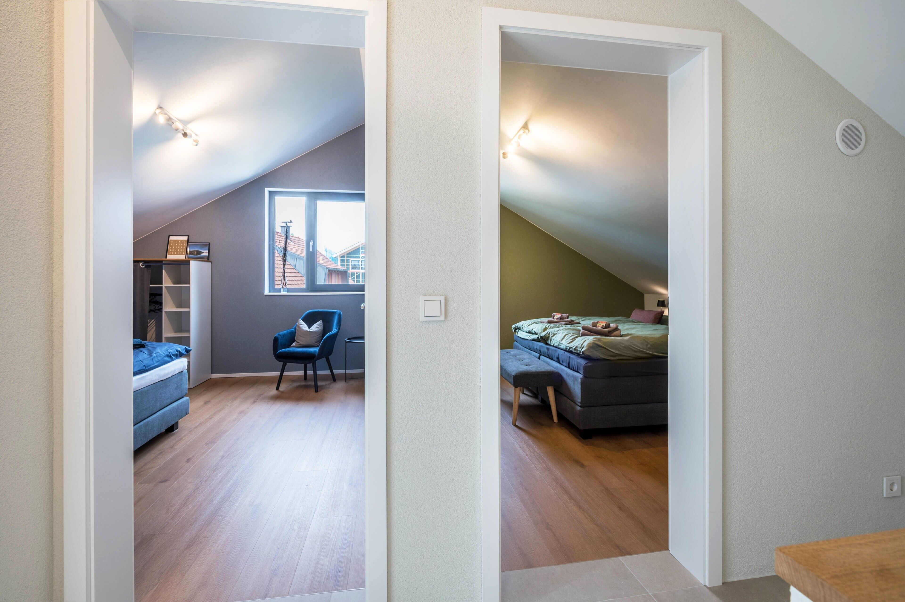 Una habitación con cama, una silla, un escritorio y una ventana que ofrece vistas a edificios.