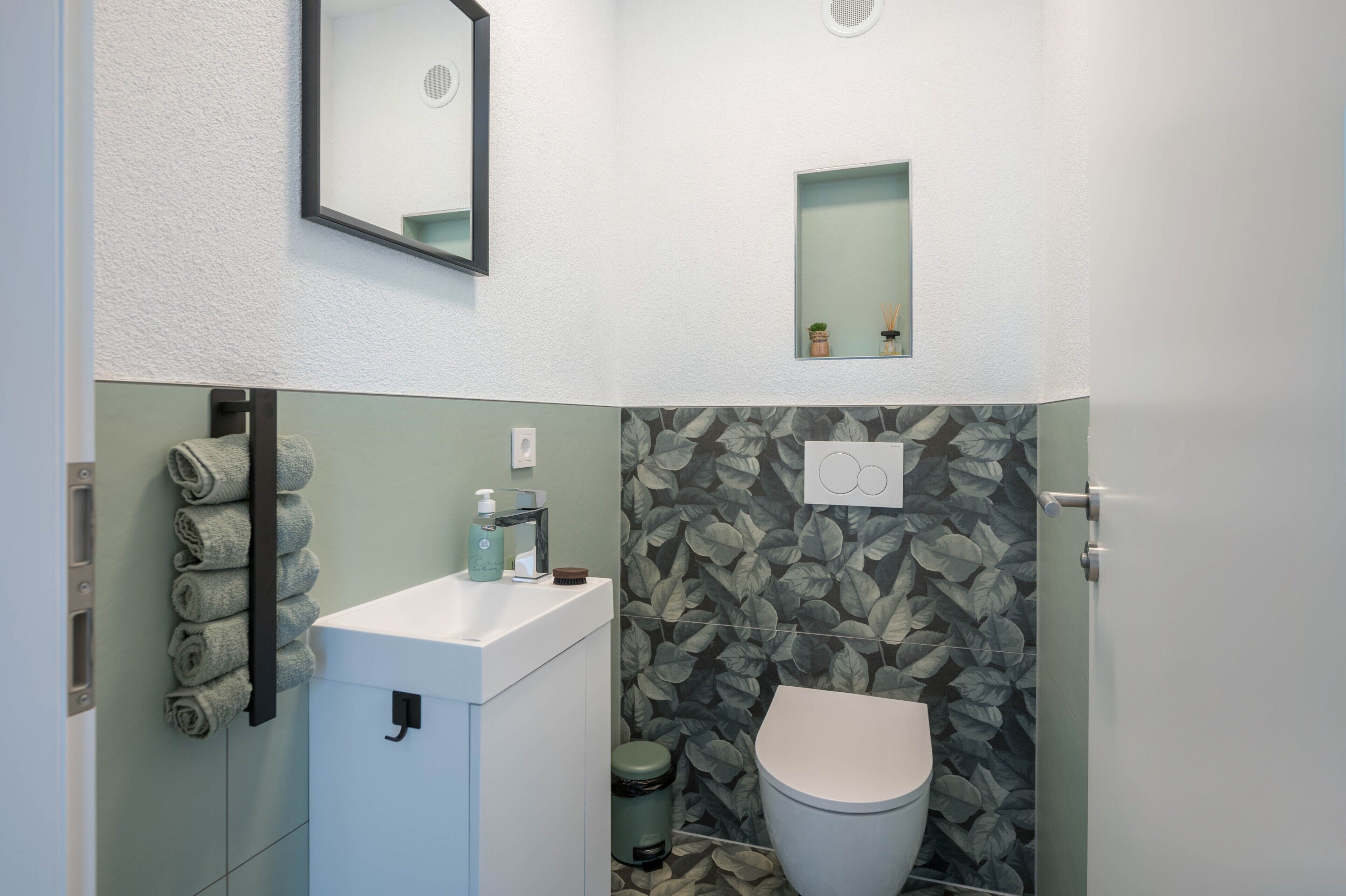 Un bagno con il water, un lavandino, un portasciugamani e uno specchio.