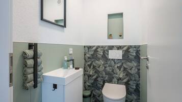 Un bagno con il water, un lavandino, un portasciugamani e uno specchio.