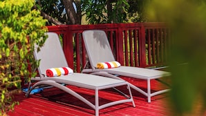 Deux chaises longues avec coussins sur une terrasse rouge.