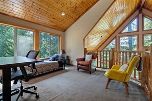 A spacious room with a large desk, a sofa, and two chairs. There are large windows providing a view of the outdoors.