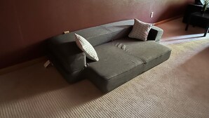 Un soggiorno moderno con un divano grigio, due cuscini decorati, un piccolo tavolino e una pianta in vaso.