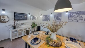 Un coin repas avec une table en bois, des assiettes bleues et blanches, un pichet blanc et des lampes fixées au mur.