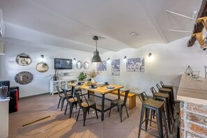 A dining area with a wooden table, black chairs, and a hanging light fixture.