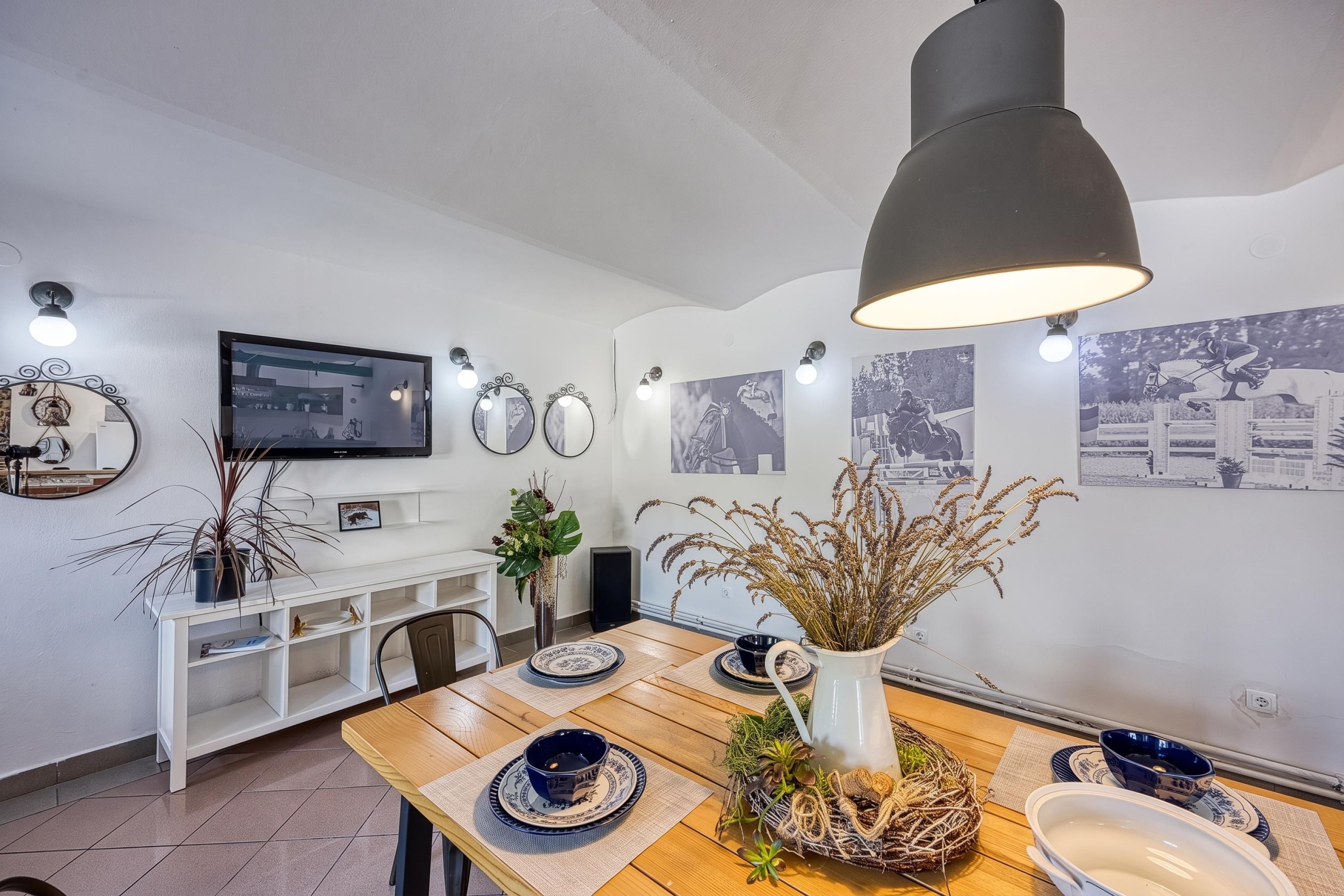 A dining area with a wooden table, blue and white plates, a white pitcher, and wall-mounted mirrors.