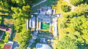 Ett flygbildsfoto av en historisk byggnad med en central innergård, omgiven av tät vegetation.