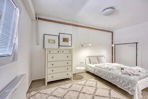 A bedroom with a bed, a dresser, a bedside table, a lamp, and a radiator.