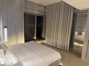 A modern hotel room with a large bed, a city view through floor-to-ceiling windows, and a minimalist design.