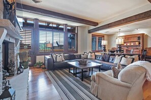 A spacious living room with a fireplace, large windows, a sectional sofa, and a dining area.