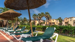 A row of green lounge chairs with white frames on a tiled patio, surrounded by palm trees and a clear blue sky. - Residence Baia delle Palme Unit 1-Studio (Santa Margherita di Pula)