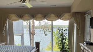 A bedroom with a large bed, a ceiling fan, a view of a lake, and a dresser. - Beautiful View of Main Channel 2 Bed/2 Bath Condo w/ Pools, Pickleball & Tennis! (Village of Four Seasons)