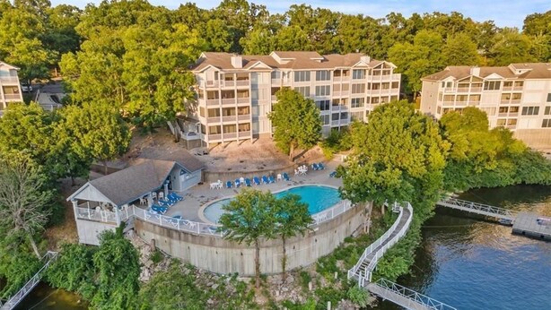 A waterfront hotel with a pool, multiple balconies, and a dock. - Beautiful View of Main Channel 2 Bed/2 Bath Condo w/ Pools, Pickleball & Tennis! (Village of Four Seasons)
