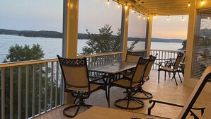 An outdoor patio with a table and chairs, overlooking a body of water. - Beautiful View of Main Channel 2 Bed/2 Bath Condo w/ Pools, Pickleball & Tennis! (Village of Four Seasons)