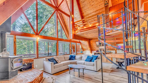 A spacious living area with a large wooden ceiling, a stone fireplace, and a cozy seating arrangement. - Woodsy Tahoe Cabin with Hot Tub and Deck (Carnelian Bay)
