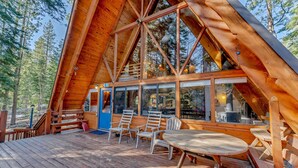 A wooden cabin with a large deck, multiple windows, and a dining area. - Woodsy Tahoe Cabin with Hot Tub and Deck (Carnelian Bay)