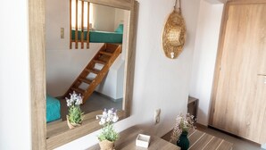 A room with a wooden-framed mirror, a woven light fixture, and a wooden door. - Emmanouela Apartment Matala (Matala)
