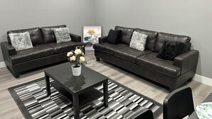 A modern living room with two dark leather sofas, a black coffee table, and a striped rug.