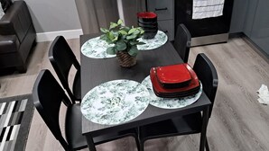 A dining area with a dark wooden table, black chairs, and a potted plant.