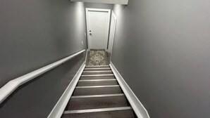 A narrow, carpeted stairway leading to a door with a white frame.