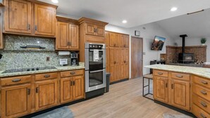 A kitchen with wooden cabinets, stainless steel appliances, granite countertops, and a built-in wood stove. - *Large Groups*Sleeps 20*Must See (Flagstaff)