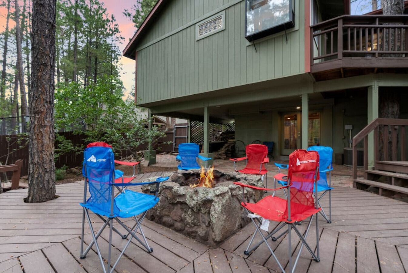 An outdoor seating area with a fire pit surrounded by blue and red folding chairs.