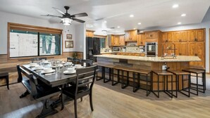 A modern kitchen with wooden cabinets, a central island with bar stools, and a dining area with a large table and chairs. - *Large Groups*Sleeps 20*Must See (Flagstaff)