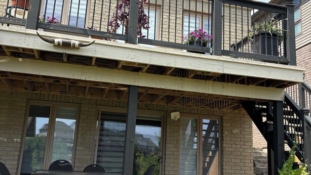 A two-story house with a balcony, outdoor seating, and potted plants. - Studio unit with one bedroom double bed and one sofa bed (Kitchener)
