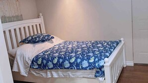 A bedroom with a bed, white headboard, and a door. - Studio unit with one bedroom double bed and one sofa bed (Kitchener)