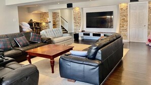 A modern living room with a leather sofa, a wooden coffee table, and a large flat-screen TV. - Studio unit with one bedroom double bed and one sofa bed (Kitchener)