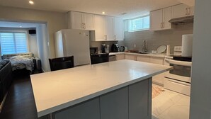 A modern kitchen with white cabinetry, a large island, and built-in appliances. - Studio unit with one bedroom double bed and one sofa bed (Kitchener)