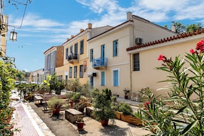 A narrow street lined with colorful buildings, potted plants, and outdoor seating areas. - Wonderful Neoclassical with Acropolis view , free parking, fireplace & terrace! (Athina)