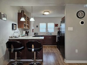 A kitchen with a central island, bar stools, a refrigerator, and a clock on the wall. - Downtown Phoenix Triplex w/ Backyard & Free (Phoenix)
