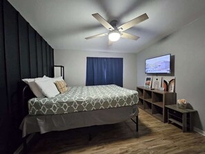 A bedroom with a bed, a ceiling fan, a TV, and a small table with decorative items. - Downtown Phoenix Triplex w/ Backyard & Free (Phoenix)
