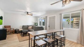 A modern living room with a sofa, a coffee table, and a dining area with bar stools.