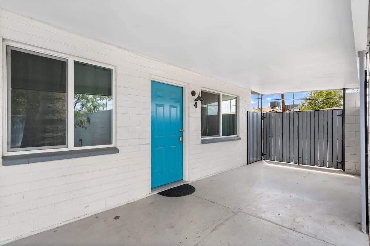 A white building with a blue door, large windows, and a gated entrance.