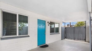 A white building with a blue door, large windows, and a gated entrance.