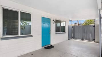 A white building with a blue door, large windows, and a gated entrance.