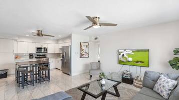 A modern living space with a kitchen, dining area, and a seating area with a television.