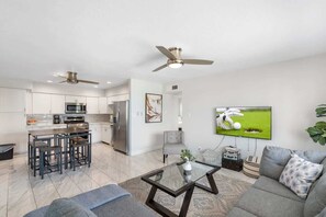 A modern living space with a kitchen, dining area, and a seating area with a television.