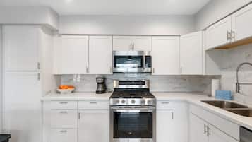 A modern kitchen with white cabinetry, a stainless steel oven, and a microwave.