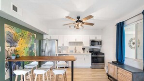 A modern kitchen with white cabinets, a wooden dining table, and bar stools.