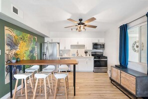 Una cocina moderna con armarios blancos, una mesa de comedor de madera y taburetes de bar.