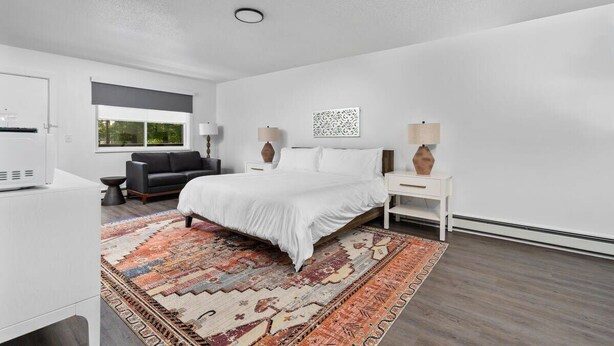 A modern bedroom with a large bed, a sofa, a desk, and a window with a view. - Peninsula One unit 18 Close to downtown and beach (Traverse City)