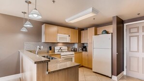 A modern kitchen with granite countertops, stainless steel appliances, and pendant lighting.