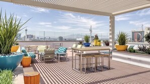 A rooftop terrace with seating, a table, and potted plants.