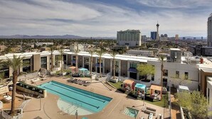 A hotel with a swimming pool, palm trees, and a city skyline in the background. - Sparkling Juhl byFremont-1 queen 1 sofa bed TONS of Amenities (Las Vegas)