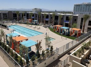 A rooftop pool with lounge chairs, a small pool area, and a view of the cityscape.